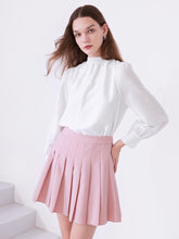 A lady wears a pink pleated skirt.